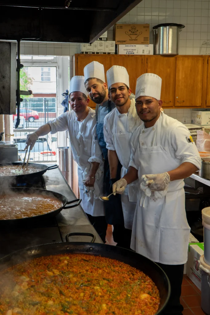 Catering: Taberna del Alabardero chefs smiling beside a large paella pan