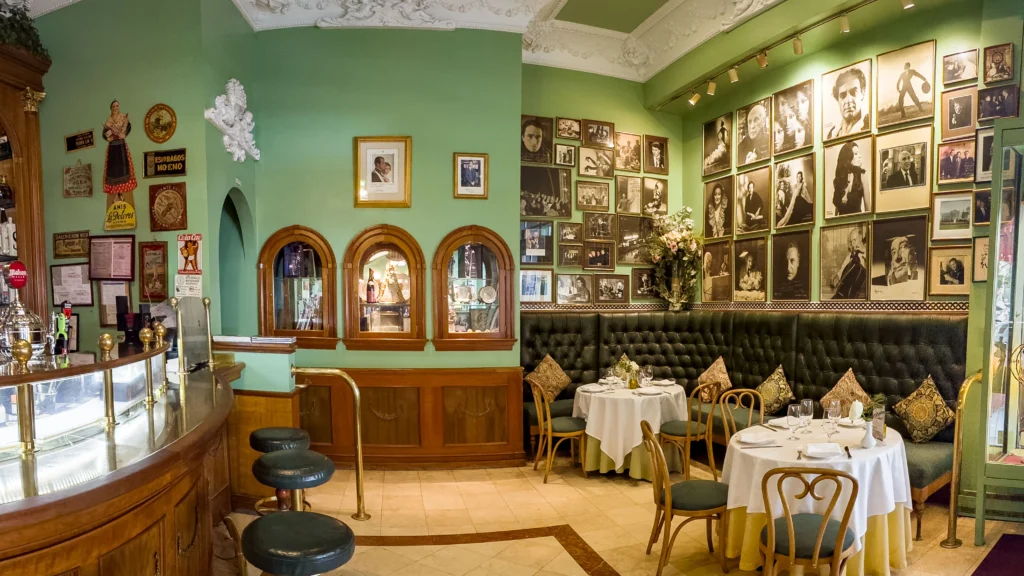 Bar at Taberna del Alabardero: bar area with tables and framed photos on the wall