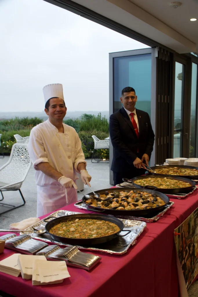 Catering: chef and server beside paella pans at an outdoor catered event