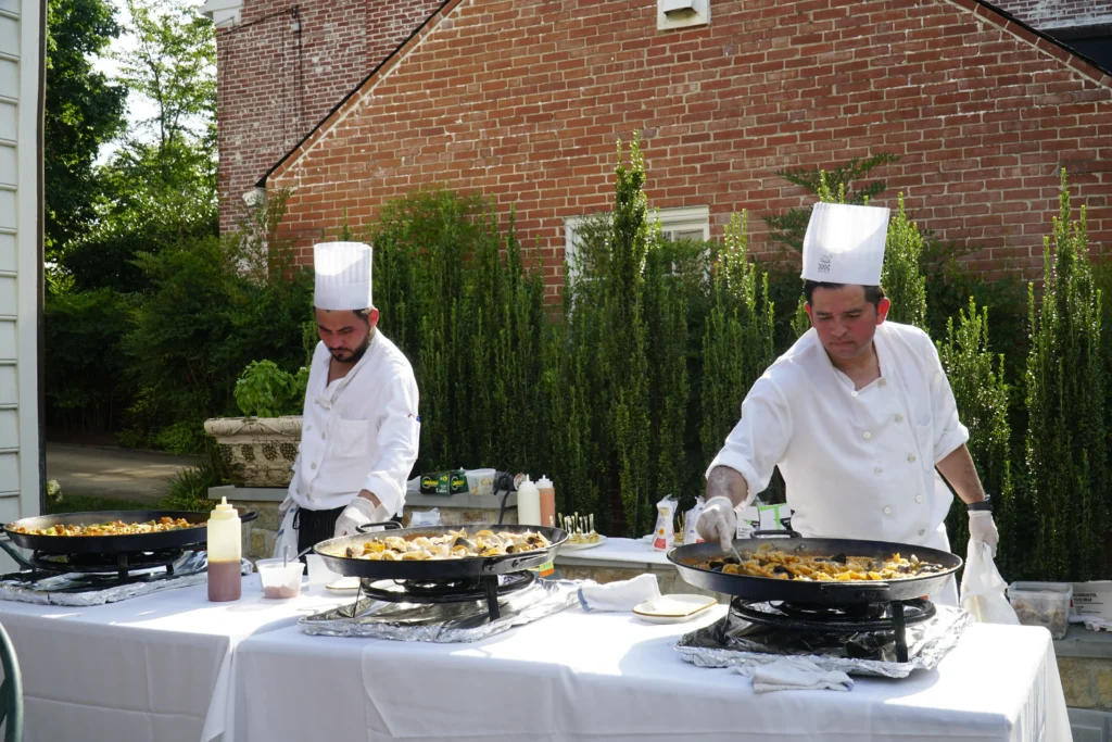 Catering: two chefs cooking paella outdoors at a catered event