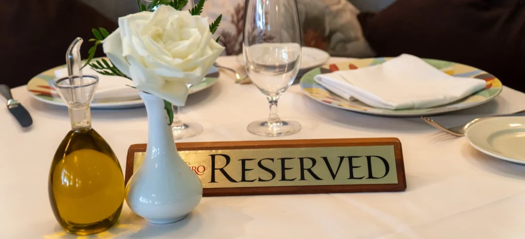 Reservations: reserved sign on a table with a rose and olive oil